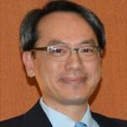 Man with glasses smiles against an orange background in jacket and collared shirt