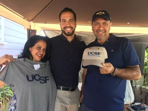 Ernesto Rojas in center hugging his family holding UCSF T-shirt and baseball hat