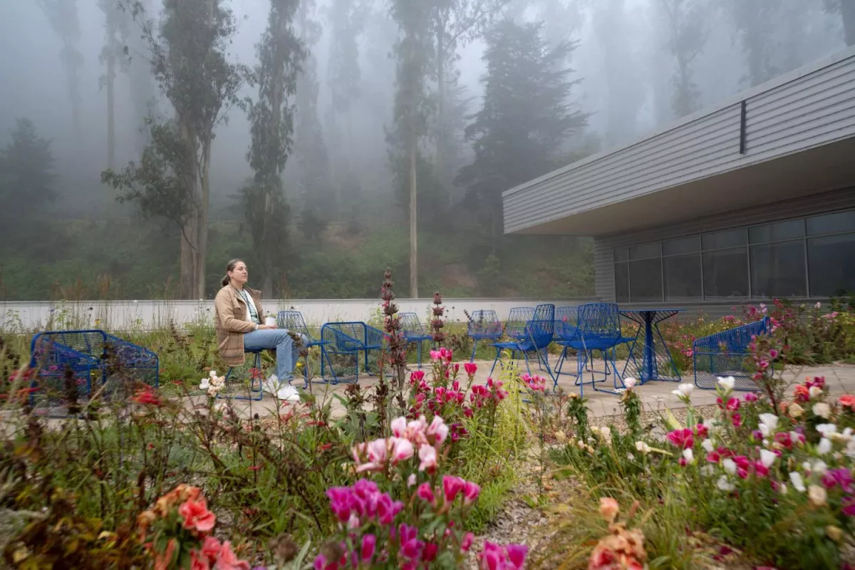 Woman sits alone in a foggy floral outdoor roof area