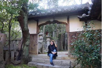 Young woman sits in front of traditional home outside