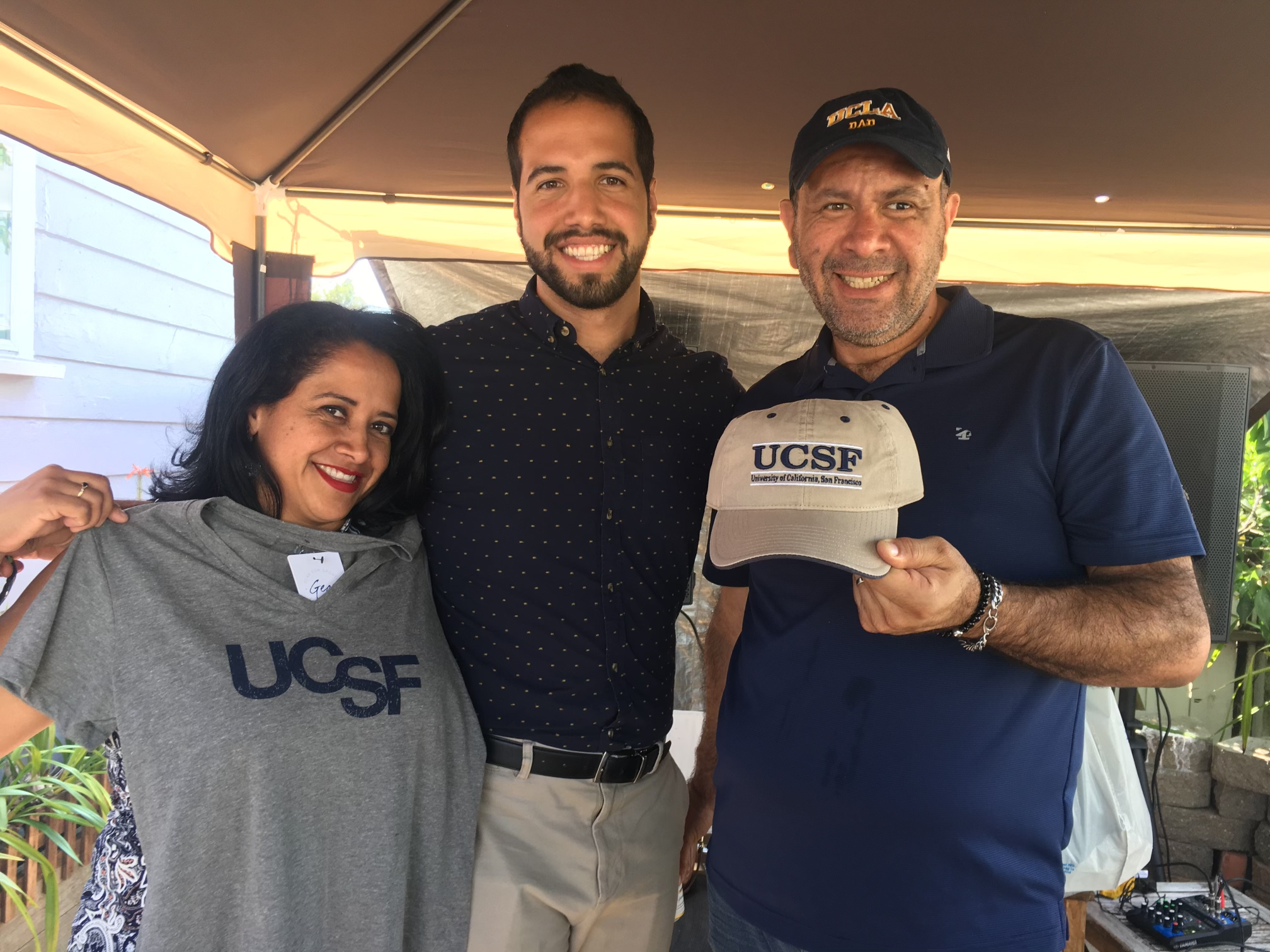 Photograph of Ernesto Rojas with family holding UCSF T-shirt and baseball hat