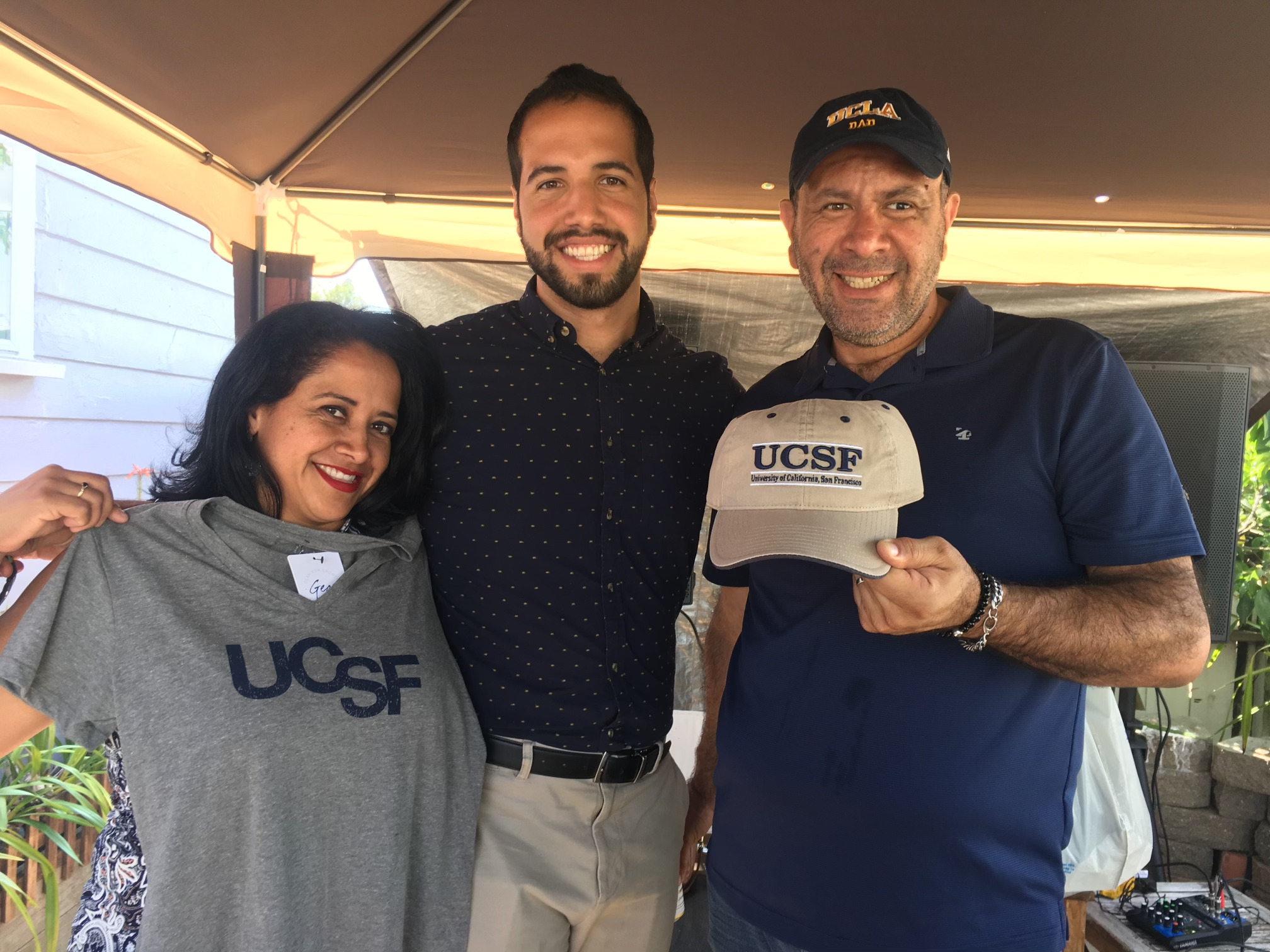 Ernesto Rojas in center hugging his family holding UCSF T-shirt and baseball hat