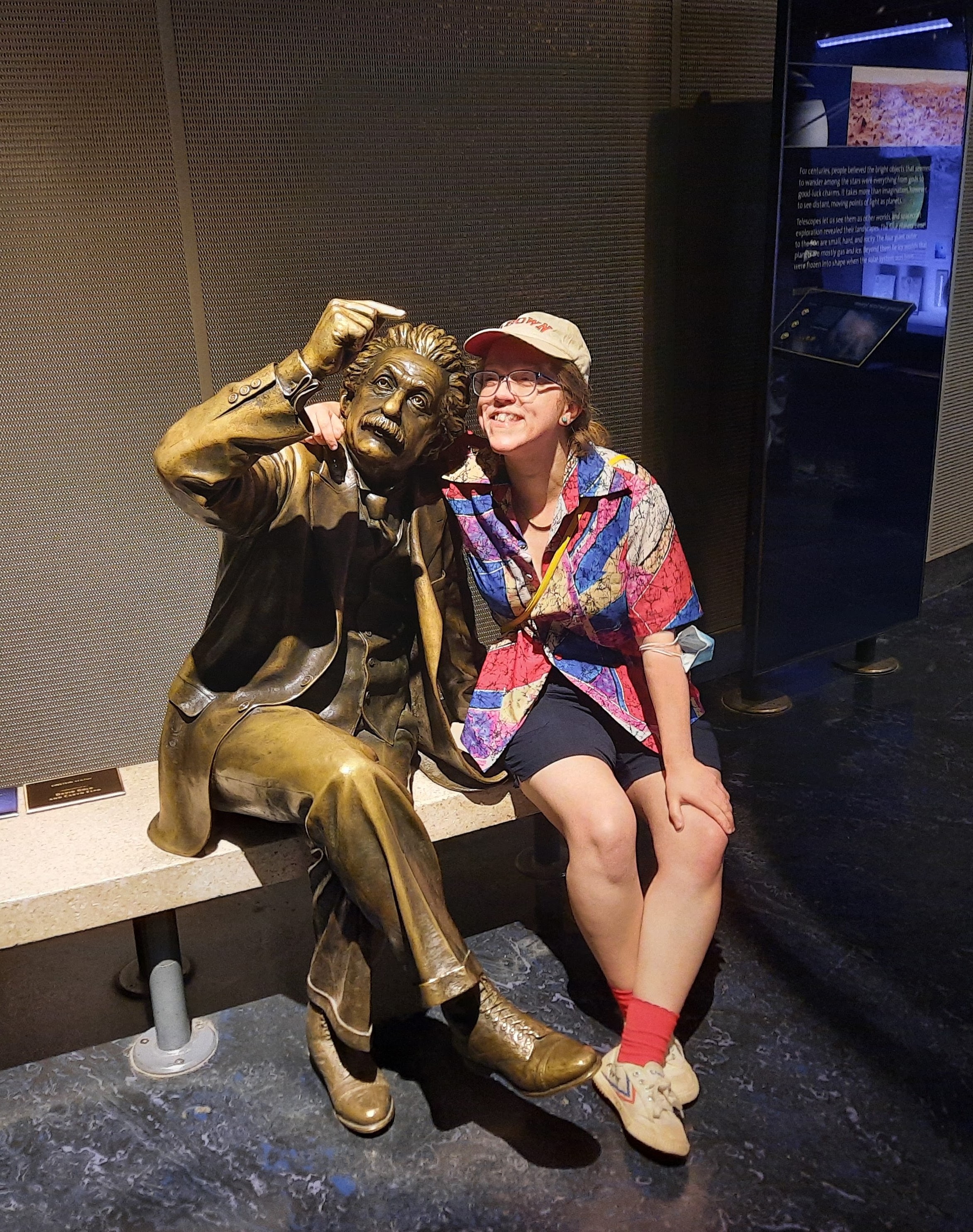 PhD candidate Simone Kurial poses with bronze statue in a dark museum setting